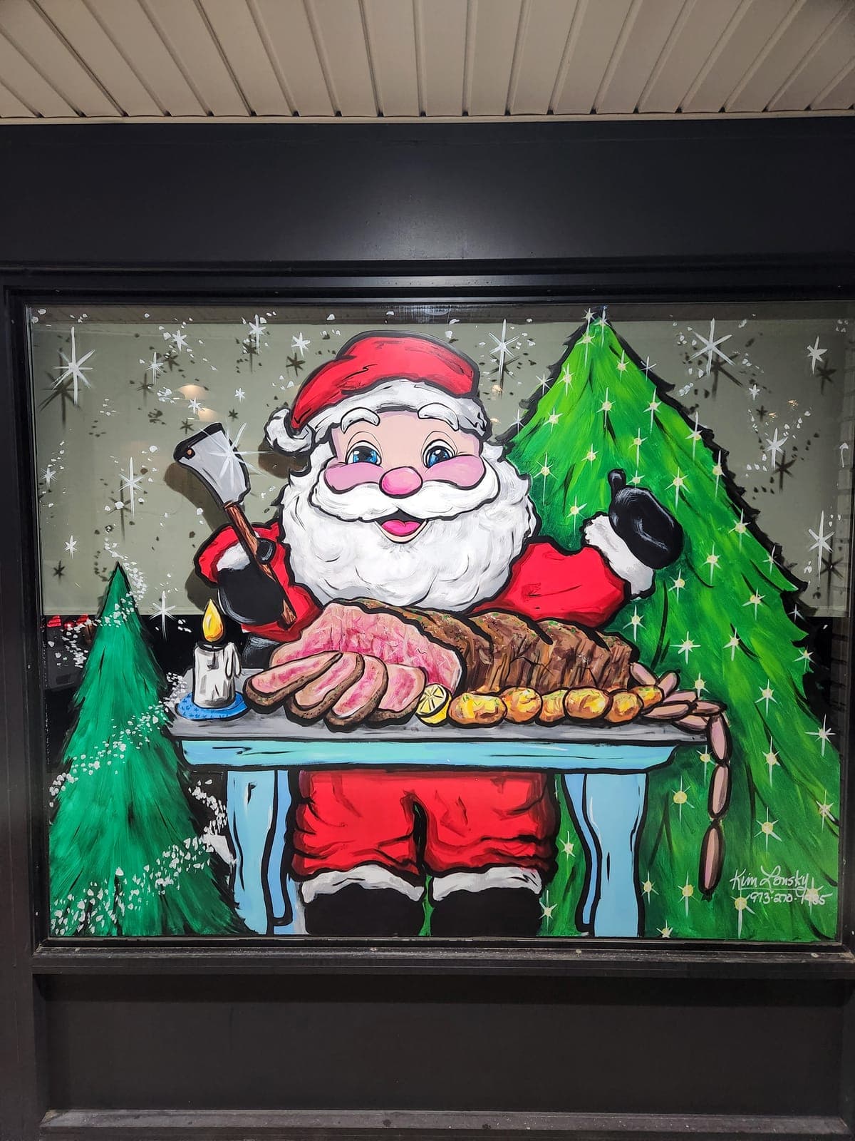 Santa Claus baking at a table, painted across a holiday storefront window